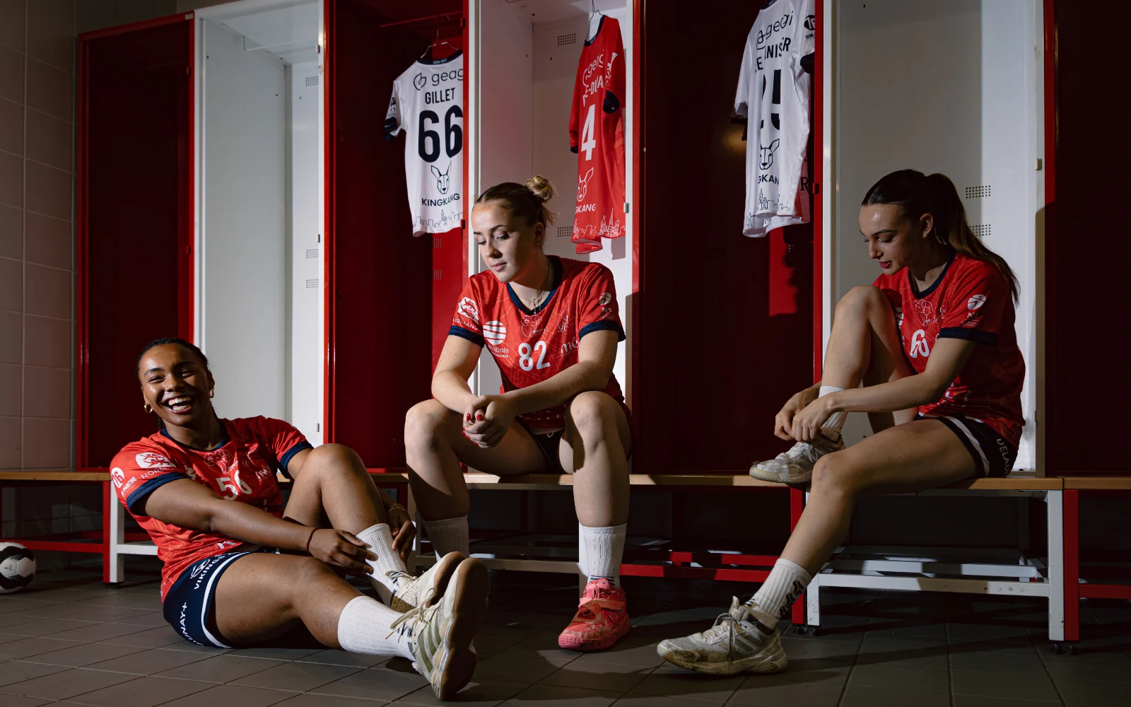 Joueurs de Rouen Handball en tenue rouge dans un vestiaire.